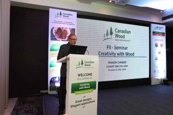 Mr. Pranesh Chhibber, Country Director, Canadian Wood at the seminar in Jaipur in a hall with black floors and white podium promoting creativity with seasoned wood species in manufacture and construction