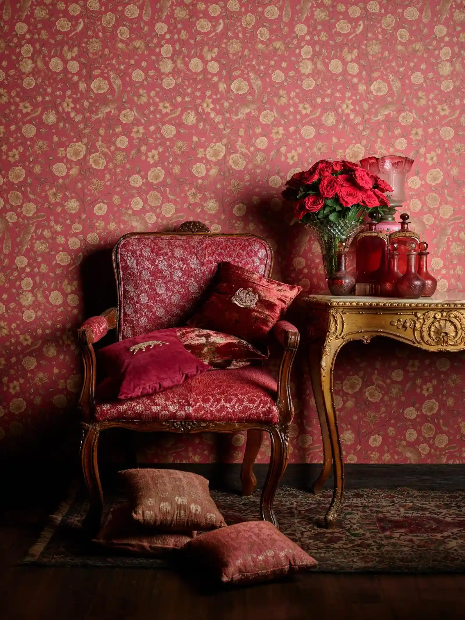 stunning red wall decor, red wooden up،lstered chair, wooden table with a flower vase placed on it, red roses