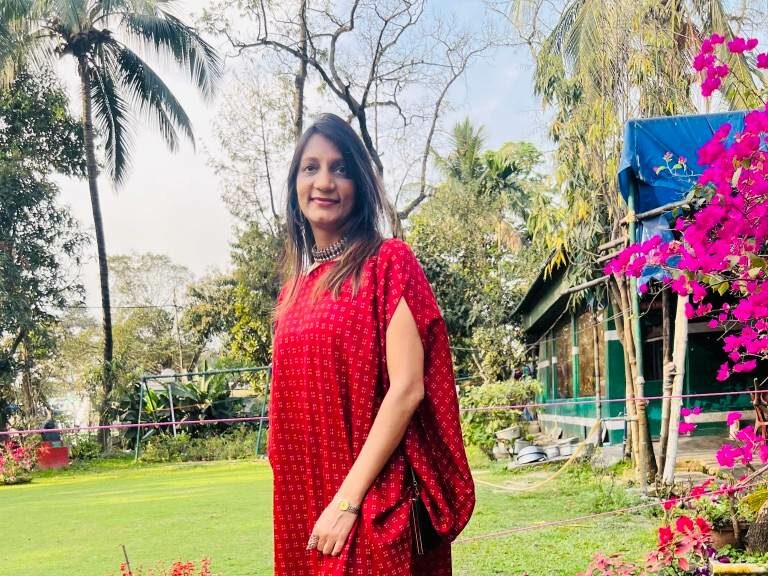 Vandana Buddhia of vermillion standing in a garden with green glass and maroon flowers, an interior designer that designs smart homes