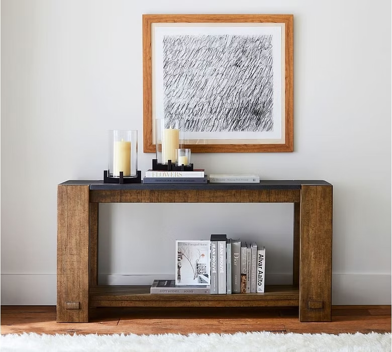 classic Parsons-style design is crafted of wood with an open shelf and four wide legs, placed in an entryway, books