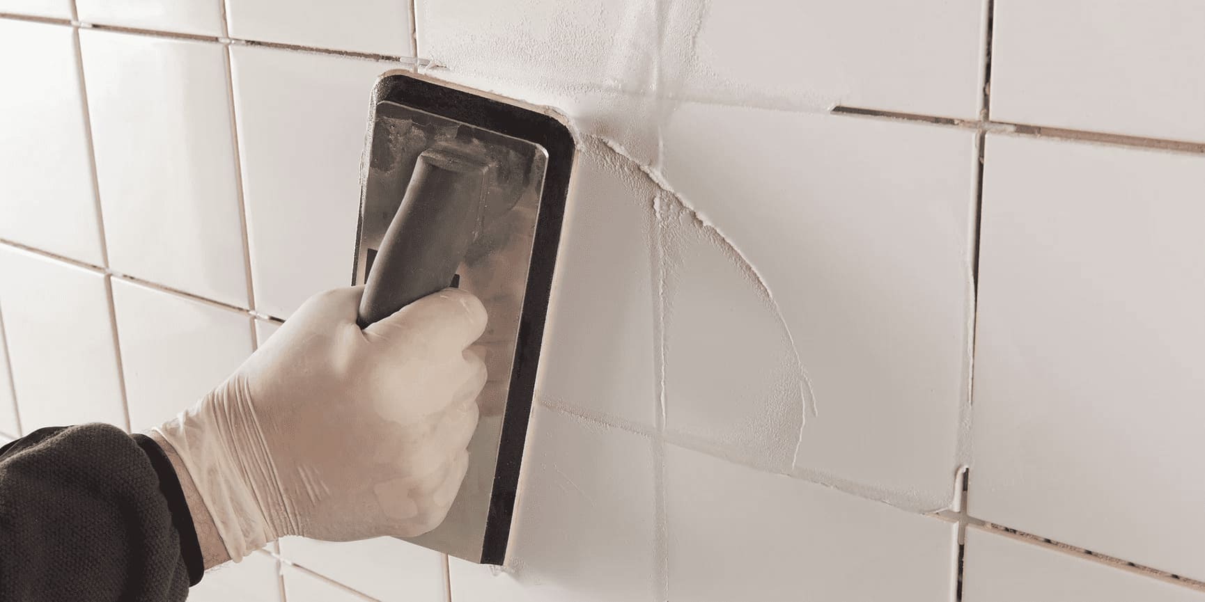 A grout float being used on a tiled wall