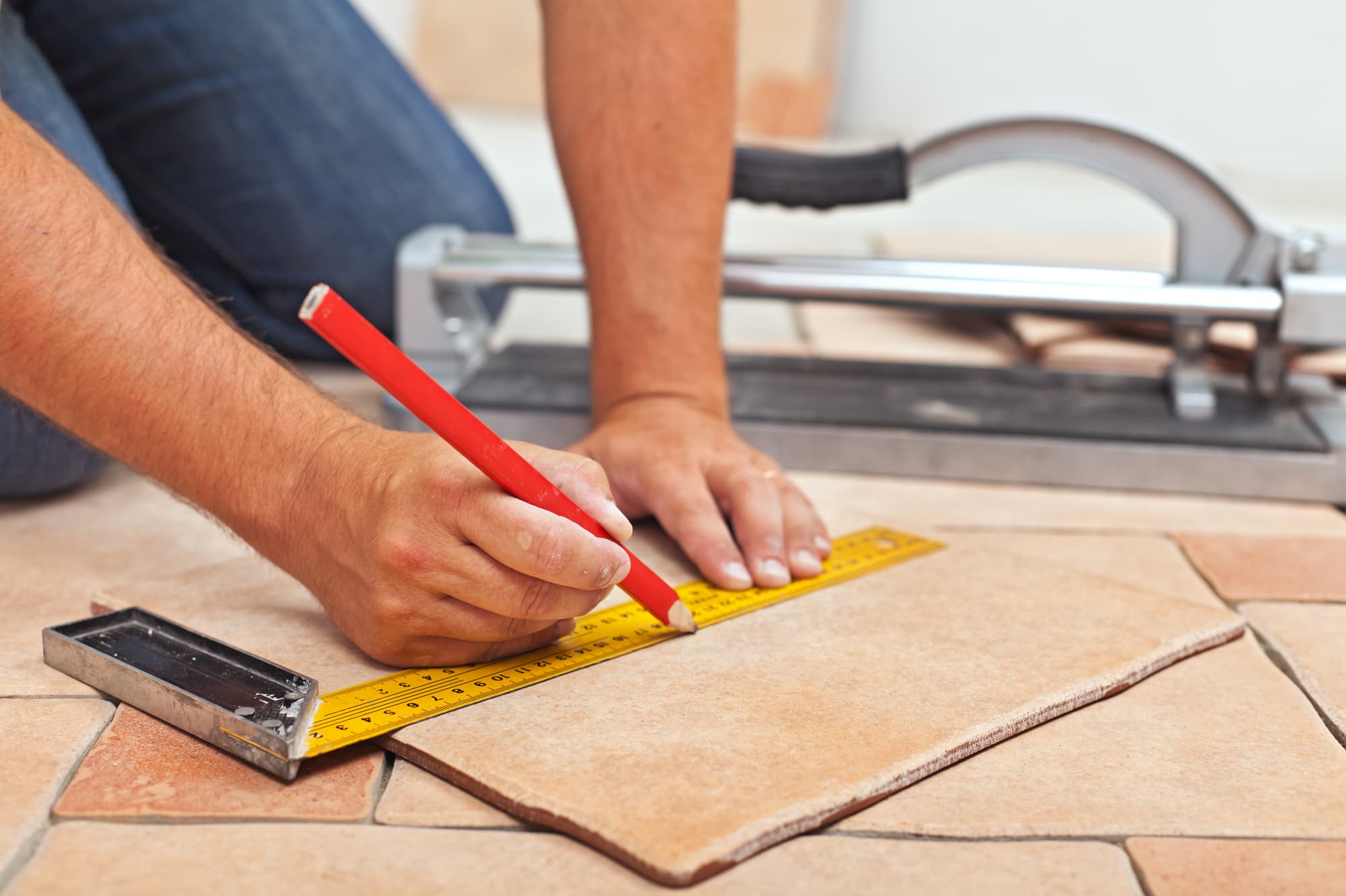 Using a pencil to measure a tile