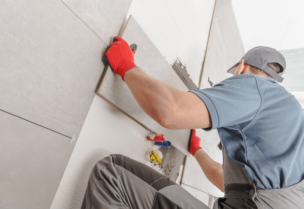 A man tiling the wall of a bathroom.