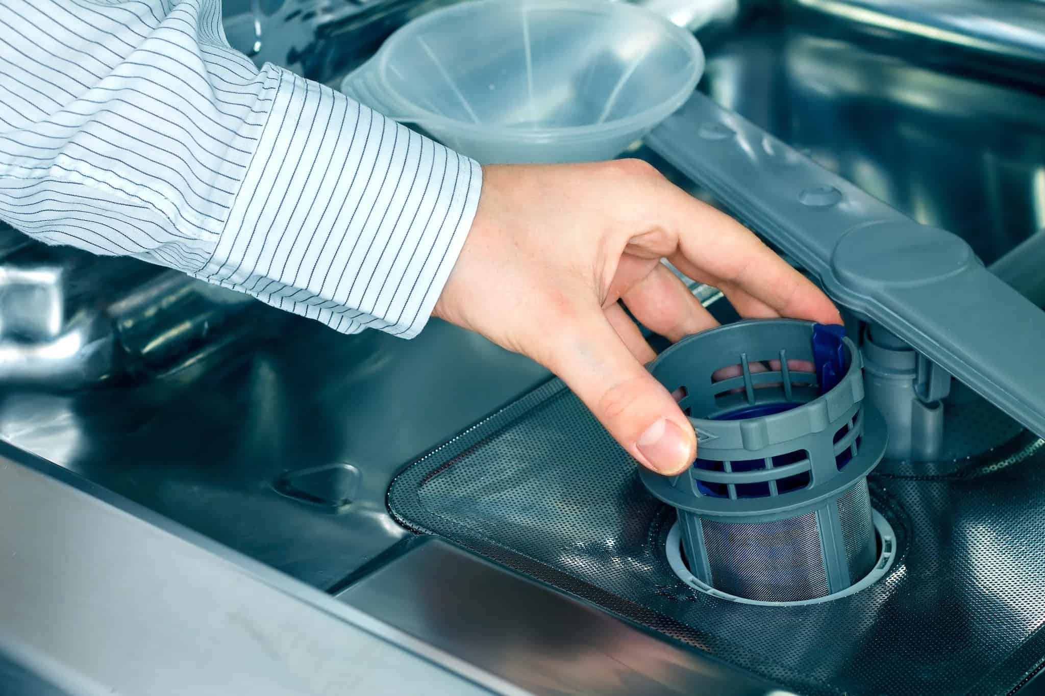 Taking out the filter of a dishwasher.