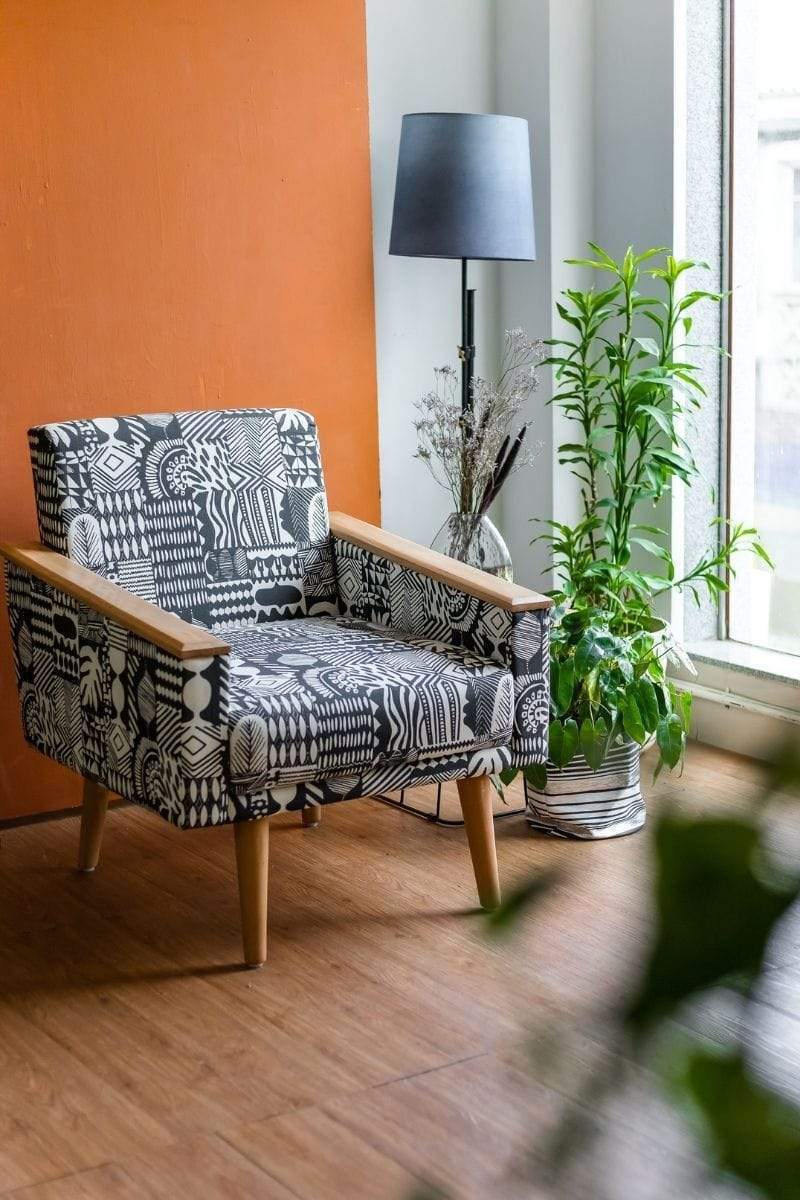 living room with a grey chair, floor lamp and orange wall