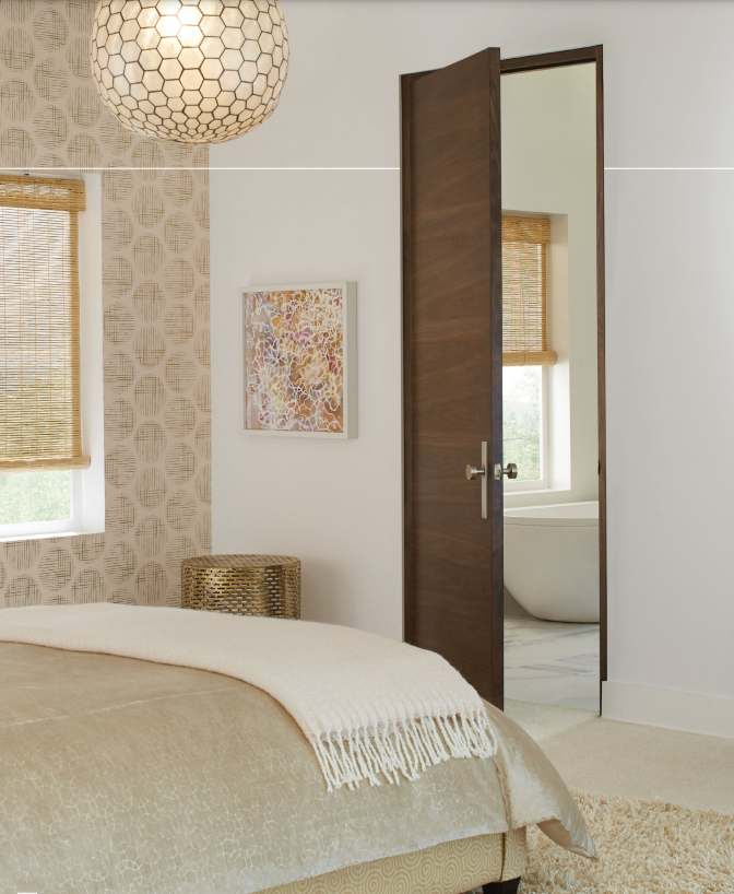 brown door in a bedroom with a bed, chandelier and wall art