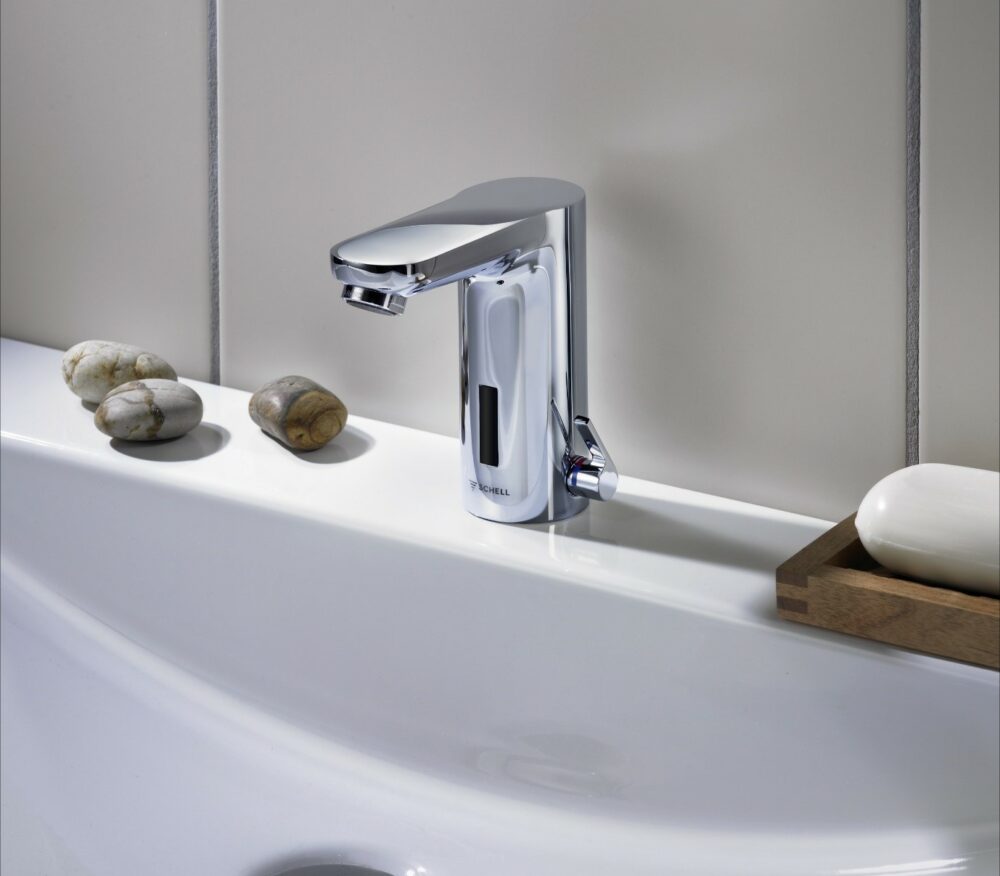 white washbasin with a silver sensor SCHELL tap with automatic stagnation flushing technology, electronic fitting and plumbing system