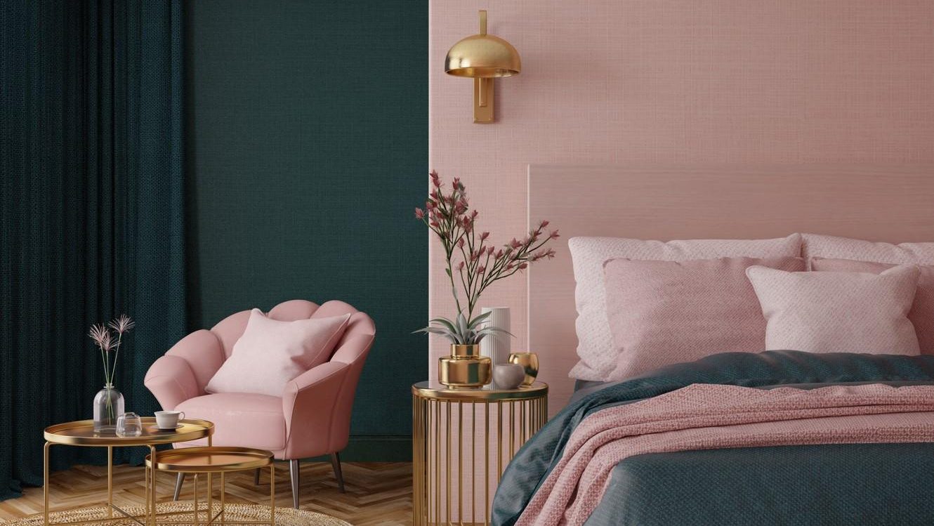 pink bedroom with a green wall, pink chair, bed, side table, brown rug and wooden floors