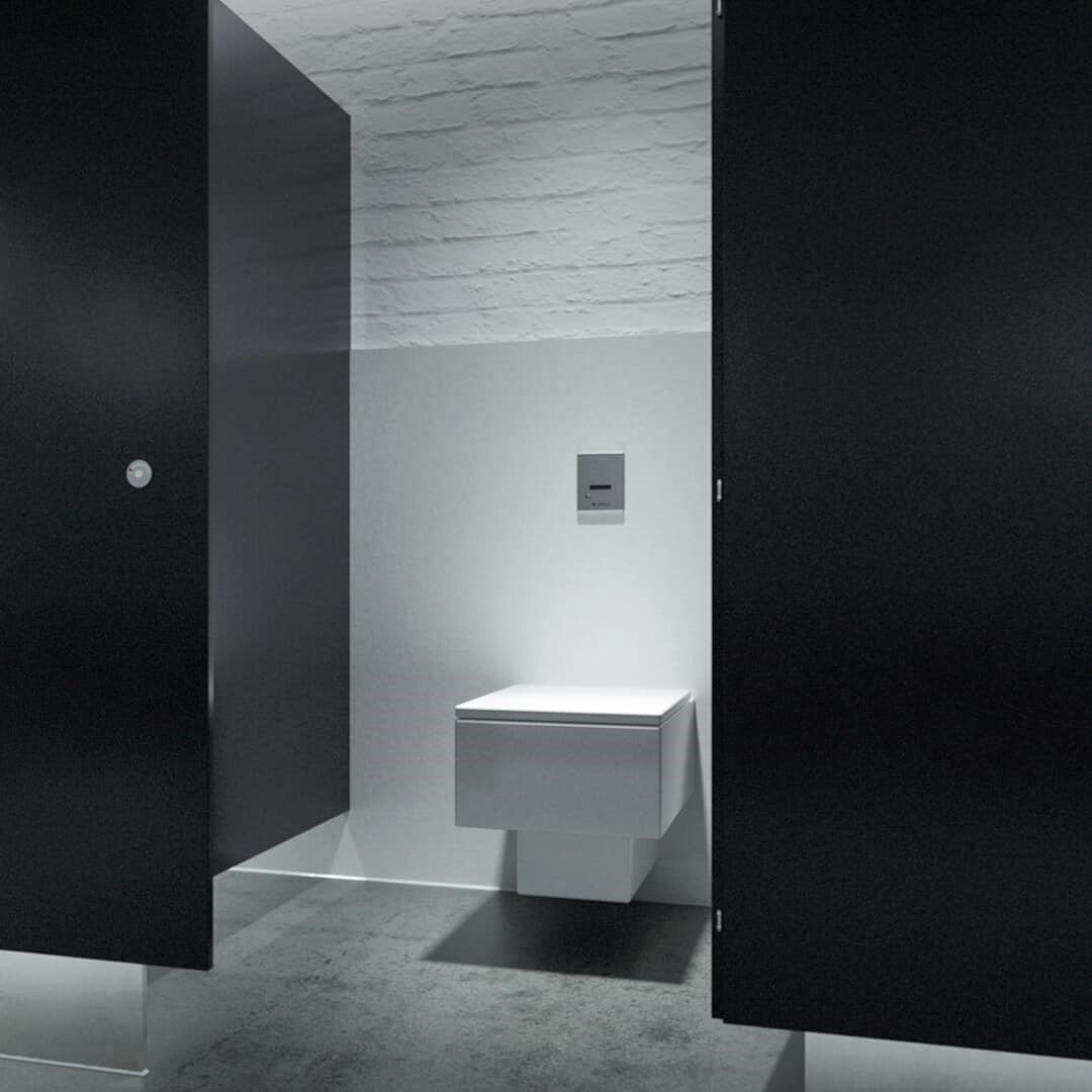 white toilet in a black bathroom stall with silver plumbing system and fittings