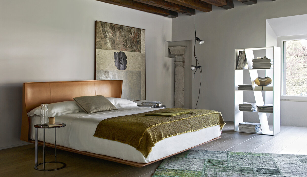 white bedroom with brown bed, rug, wall decor and shelves