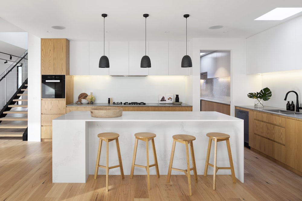 white cooking space with an island, bar stools and pendant lights