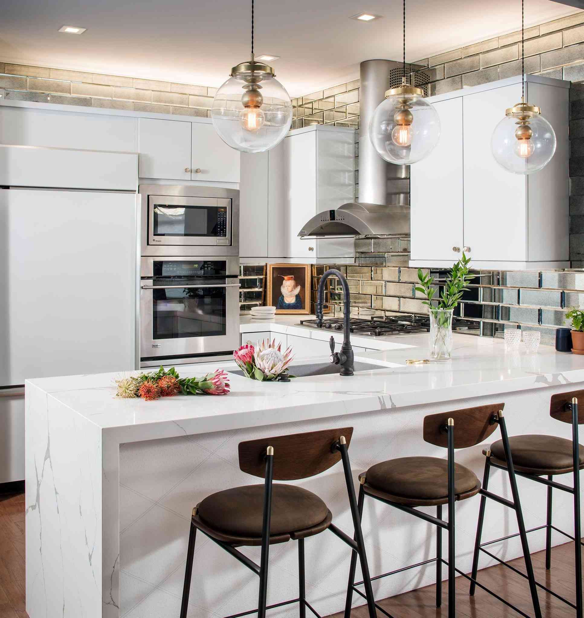 white kitchen with pendant lights, chairs, and built-in appliances