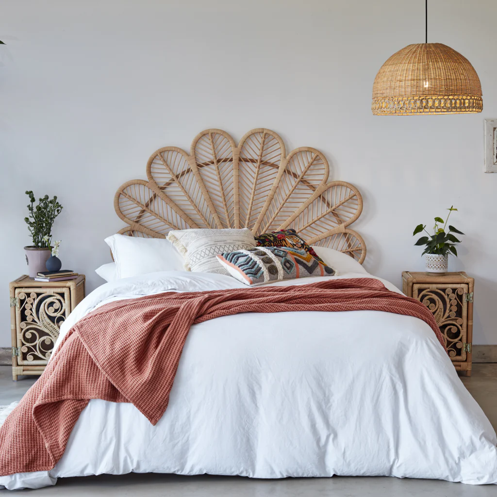 white bedroom with a rattan headboard, pendant light and side table