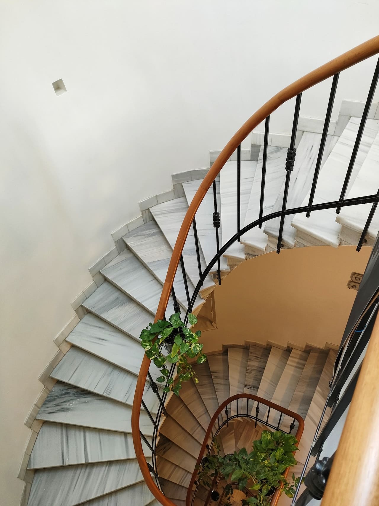 An elegant spiral staircase with metal railings and marble footsteps