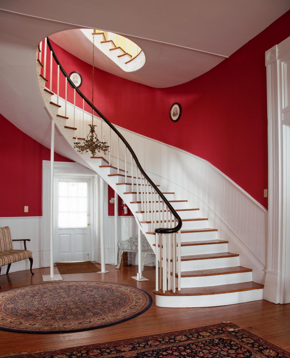 red stairway, rug in the centre, wooden flooring, metal staircase, red and white walls