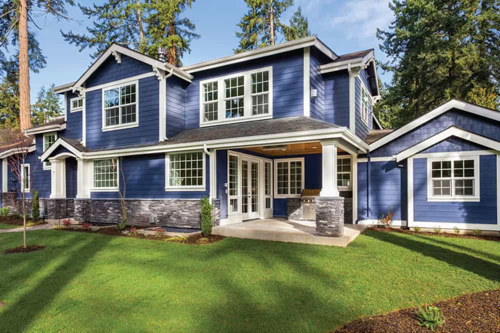 A cool home with navy blue exterior and a lawn