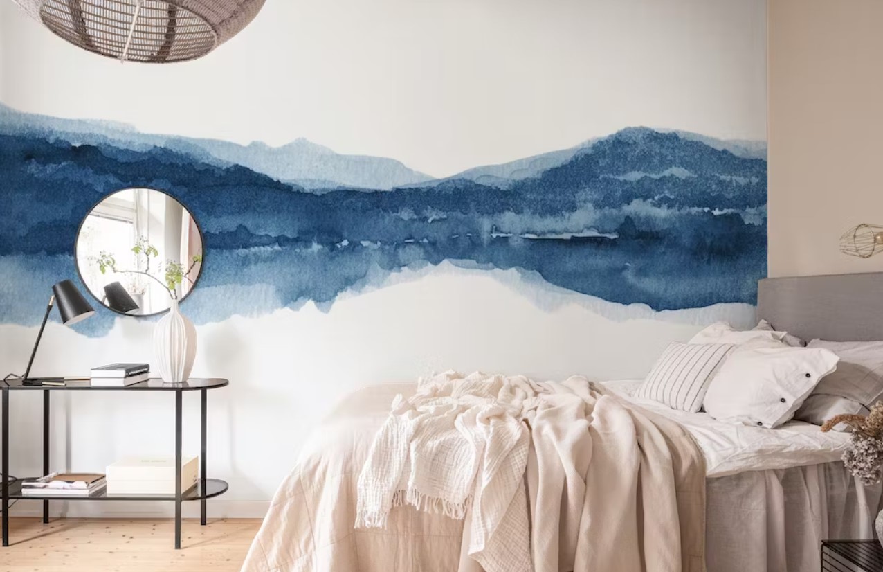watercolour painting inspired blue wallpaper in a room with a bed side table and mirror