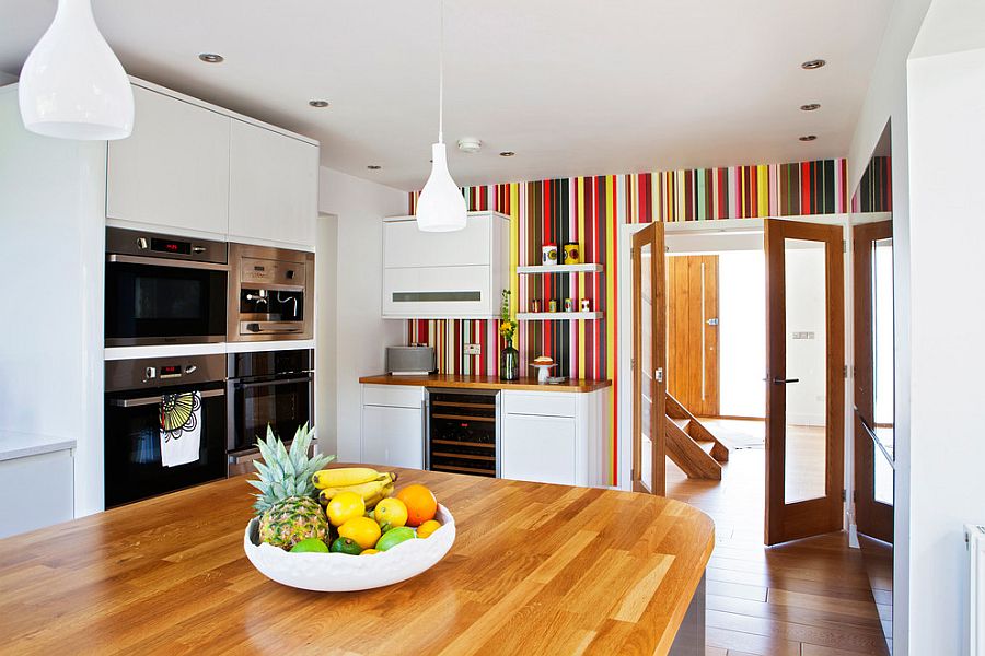 A colourful kitchen with table, hanging light and appliances