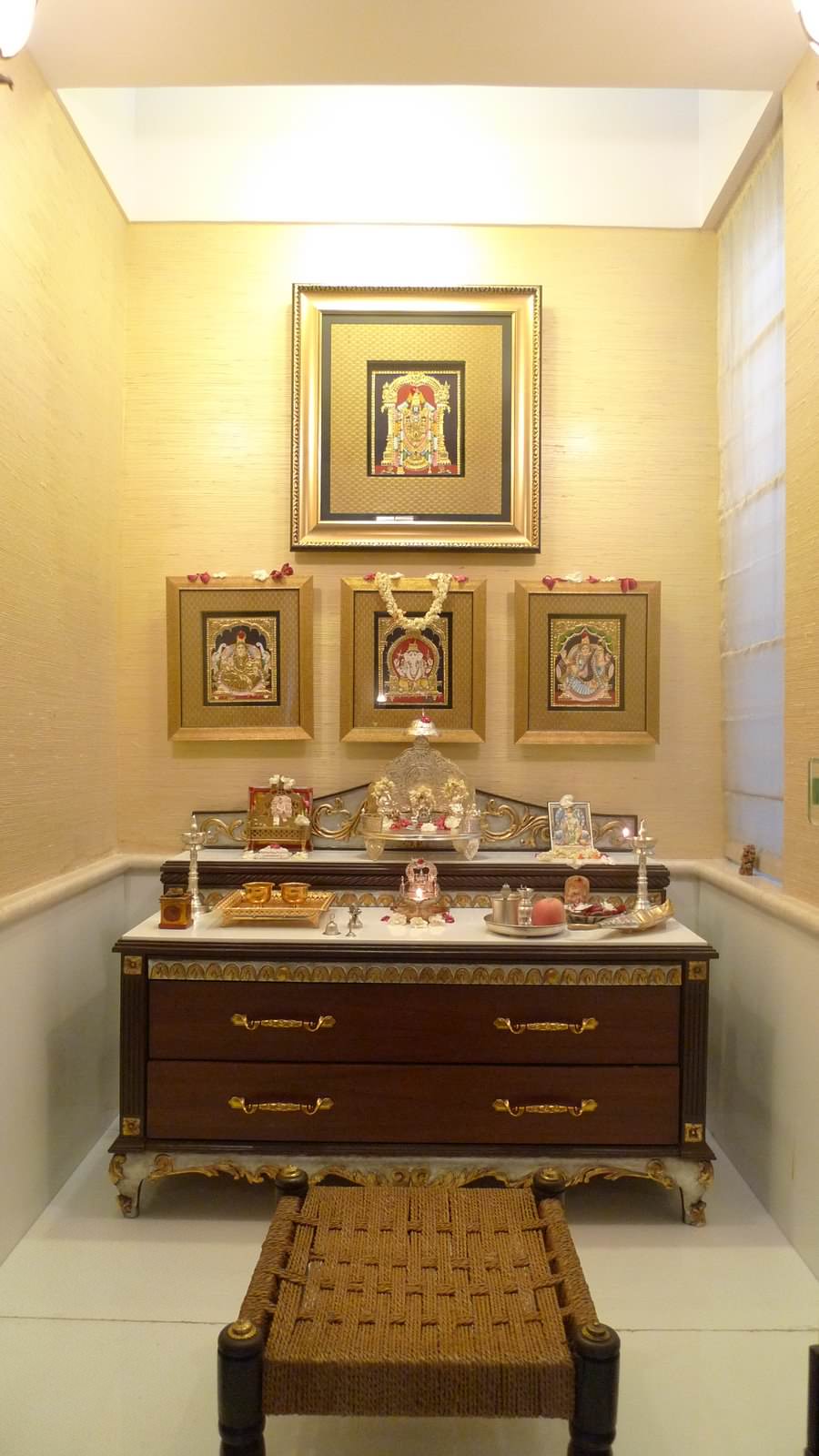 A pooja room with a satin yellow finish, idols and a table