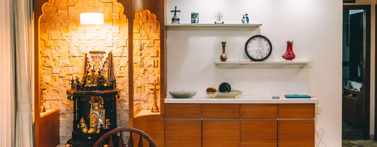 A combination of texture and plain wall in puja room with cabinets and accessories