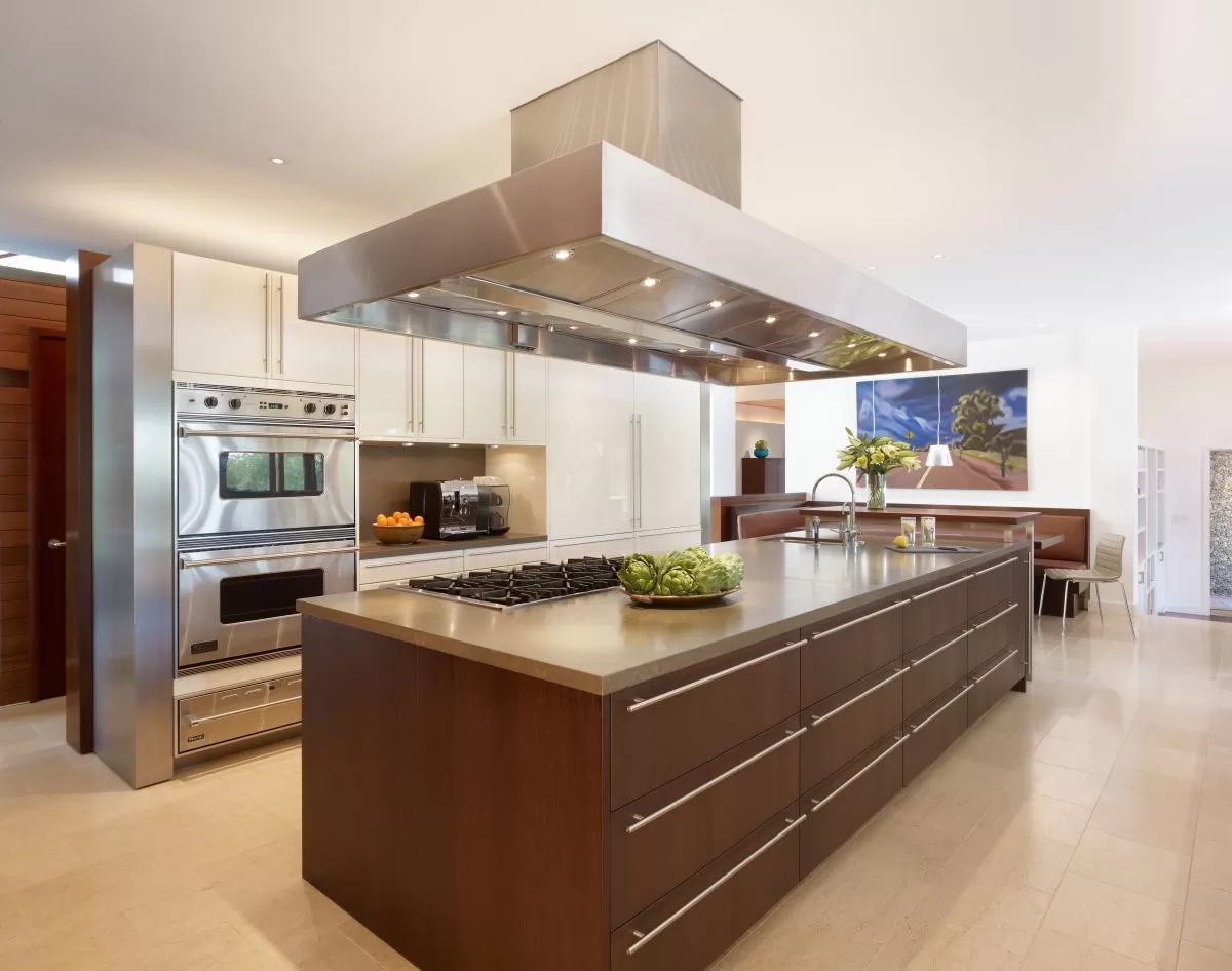 brown kitchen island with decorative lighting, modern appliances and brown wooden floors