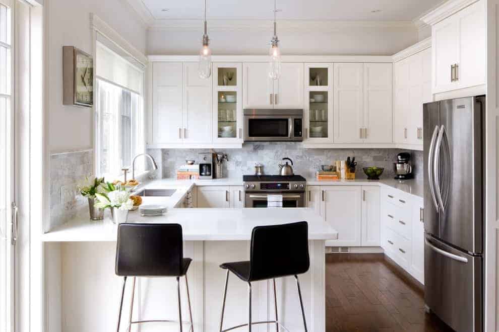 white cooking space with an island, chairs, cabinets and appliances