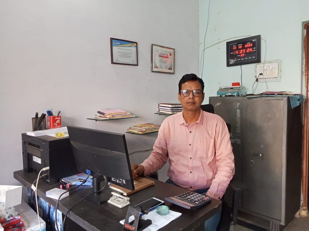 Brijendra Sharma in his office with table, chair, cupboard and computer