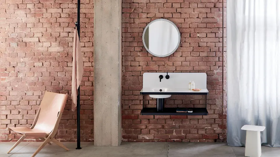 brick wall in a bathroom with washbasin, chair, and mirror 