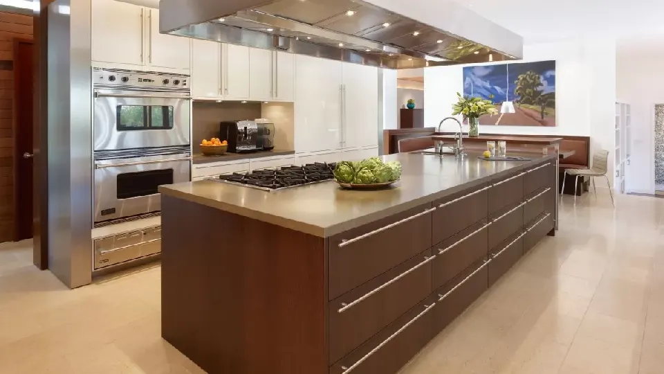 brown kitchen island with decorative lighting, modern appliances and brown wooden floors