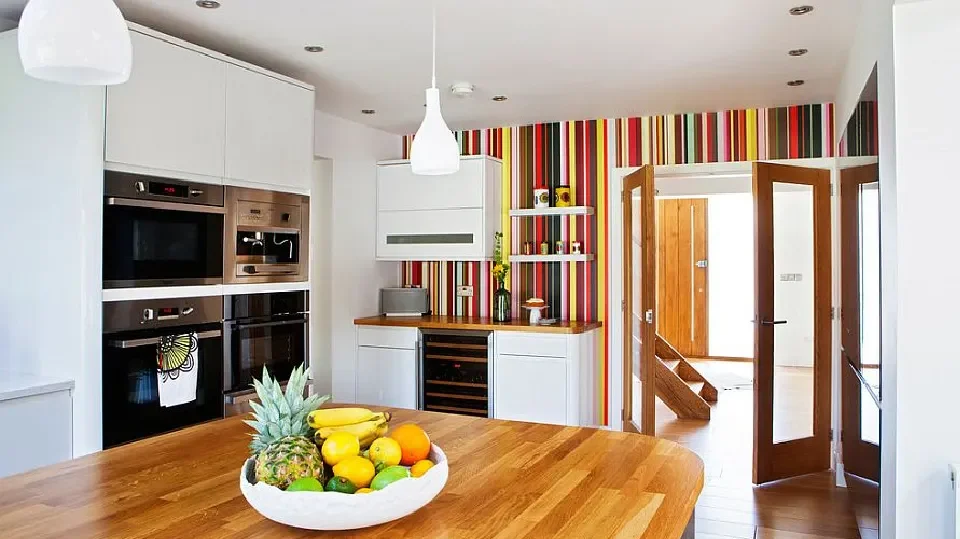 A colourful kitchen with table, hanging light and appliances