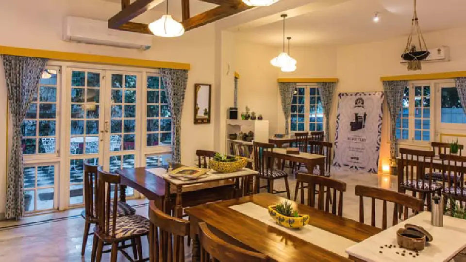 Brown interior design in one of the best cafes in India with long tables, chairs and white doors and backyard