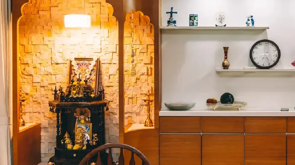 A combination of textured and plain wall in puja room with cabinets and accessories