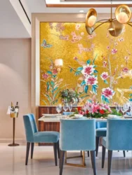 dining area, wooden table, blue chairs, yellow accent wall with floral pattern, side stand holder with bottles. white celling with brown borders, lights hanging from ceiling