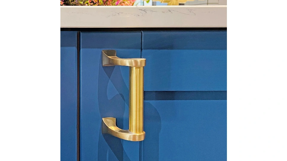 brass finish pull installed on a blue cupboard