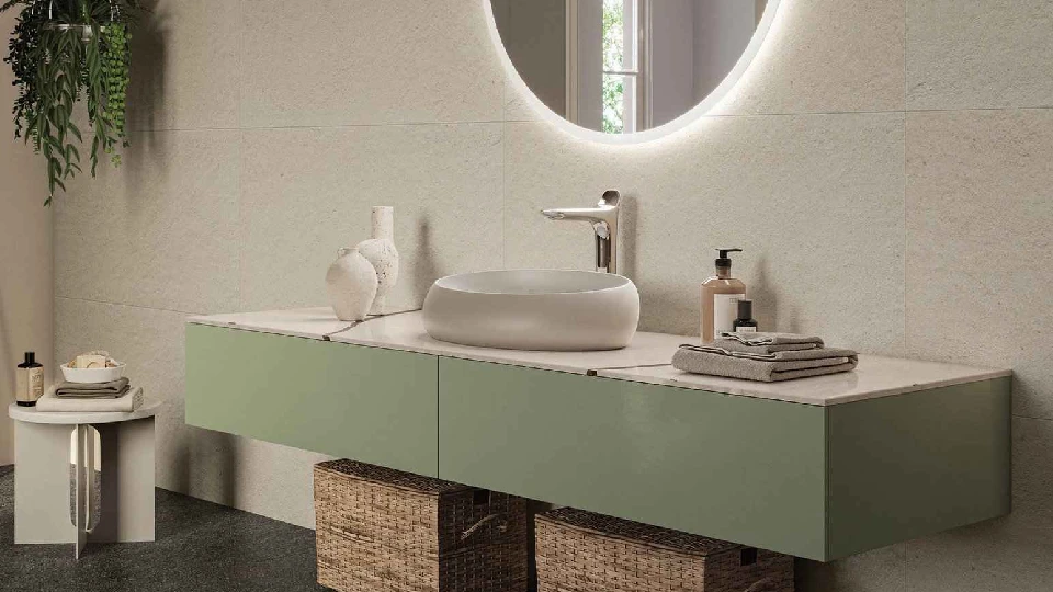 beige bath space with green cabinets, round mirror with LED lights, washbasin and wall tiles