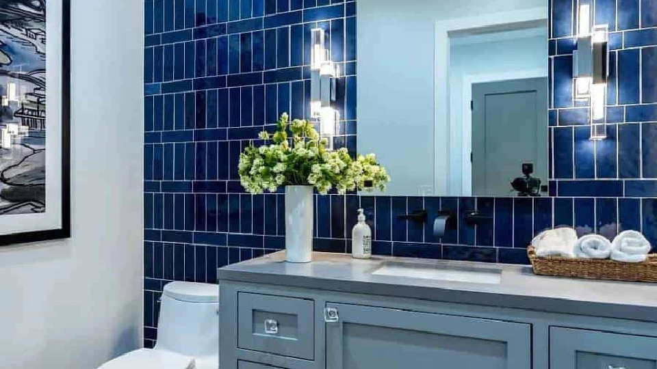 blue bathroom with yellow flowers in a vase and mirrors