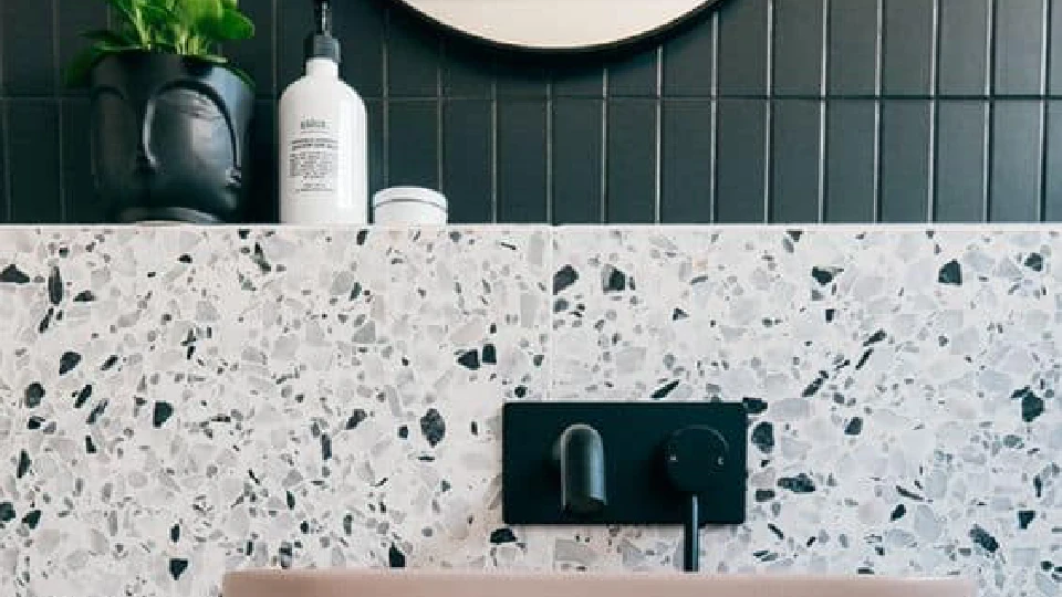 White, green tiles in a bathroom with black taps and faucets