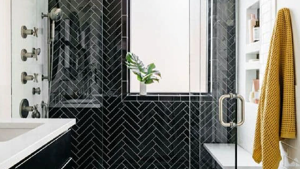 black walls in a bathroom with plants, mustard coloured towel and glass doors