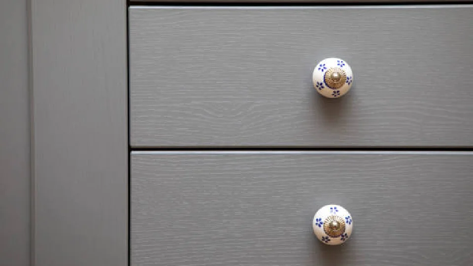 Round drawer knob attached to drawers in grey colour