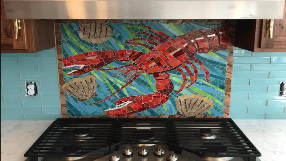 Mosaic flooring cost per sq ft on kitchen backsplash in a lobster design with blue, red, green and beige colours in it and a stovetop in front