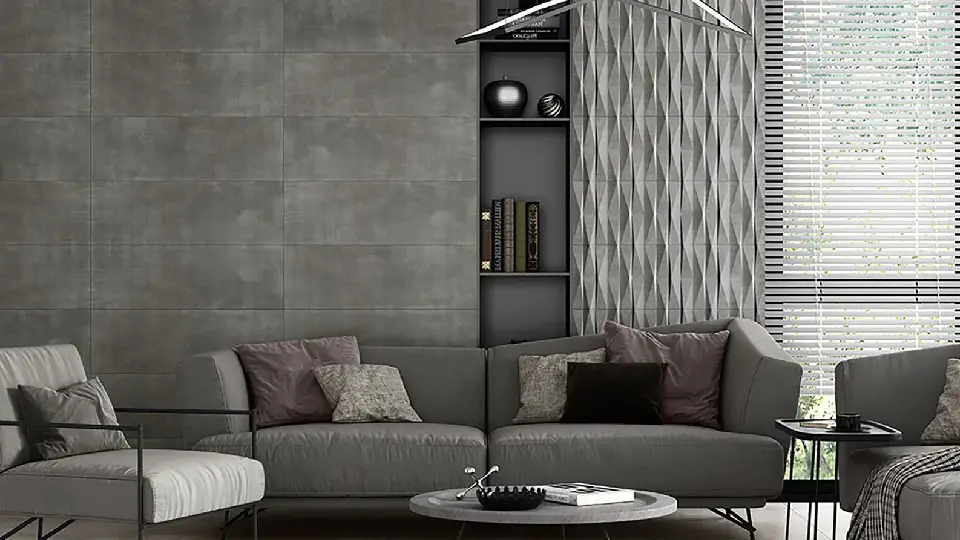 5-seater grey sofa and a round centre table, cushions and sofa throw, grey stone tile in the background, home decor pieces in a shelf