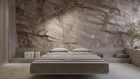 minimalistic bedroom with a dramatic stone wall, bed is low profile & appears to be floating above the floor, built-in shelving on either side of the bed with books and decor items and a potted plant on the extreme right