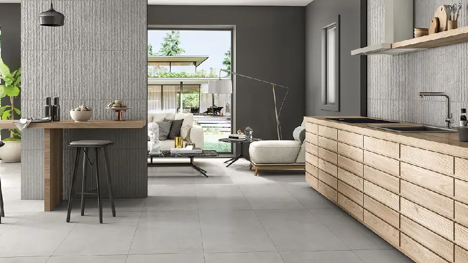 grey rock tiles on walls in an open-concept kitchen & living room, sleek wooden kitchen cabinet & sink, white sofas, floor lamp and 2 stone top tables