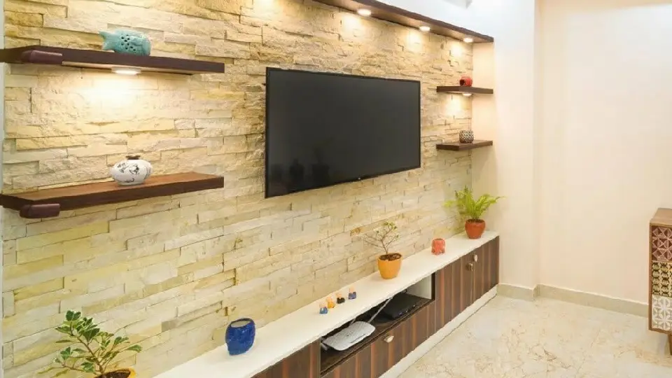 modern living room space with a TV unit, other decorative elements, plants and rock tiles wall in the background