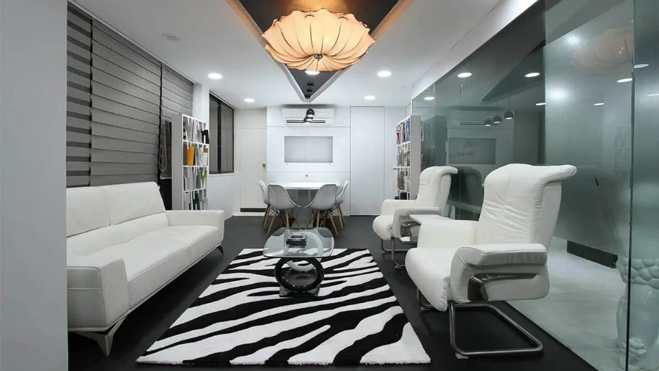 an office with white sofa, stripes rug, chairs and a lamp