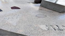 grey floor with red and white big speckles in between. Concrete base is visible at a corner