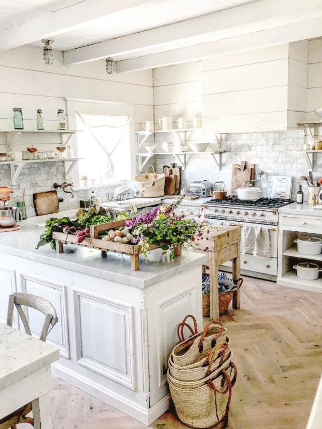 Kitchen with white cabinet, fresh vegetables, jute bags on the floor, ceramic and glass uetnsils on white hanging sheleves