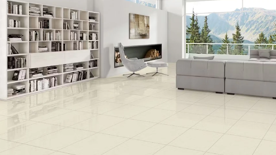 Cream coloured polished vitrified tiles in glossy finish in the living room with bookshelves and sofa