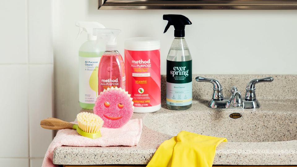 bathroom cleaning products on wash basin with gloves, scrubs and brush