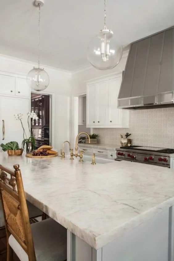 white textured quartzite countertop with wooden chairs and glass pendants. 